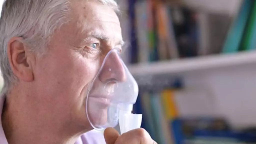 Man with pulmonary fibrosis uses oxygen mask at home to protect himself from COVID-19