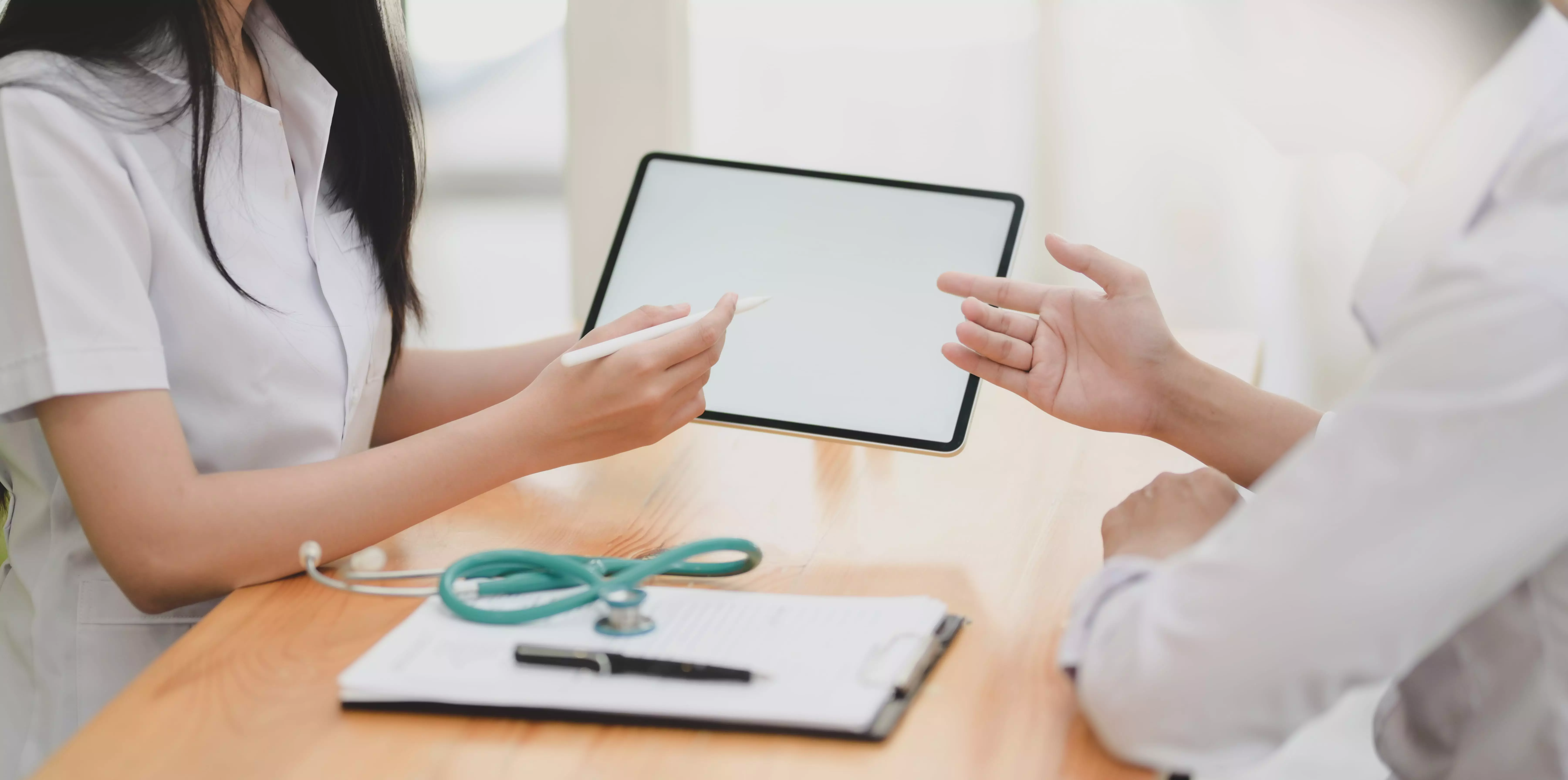 Female doctor with stethoscope explaining something on a tablet to a patient