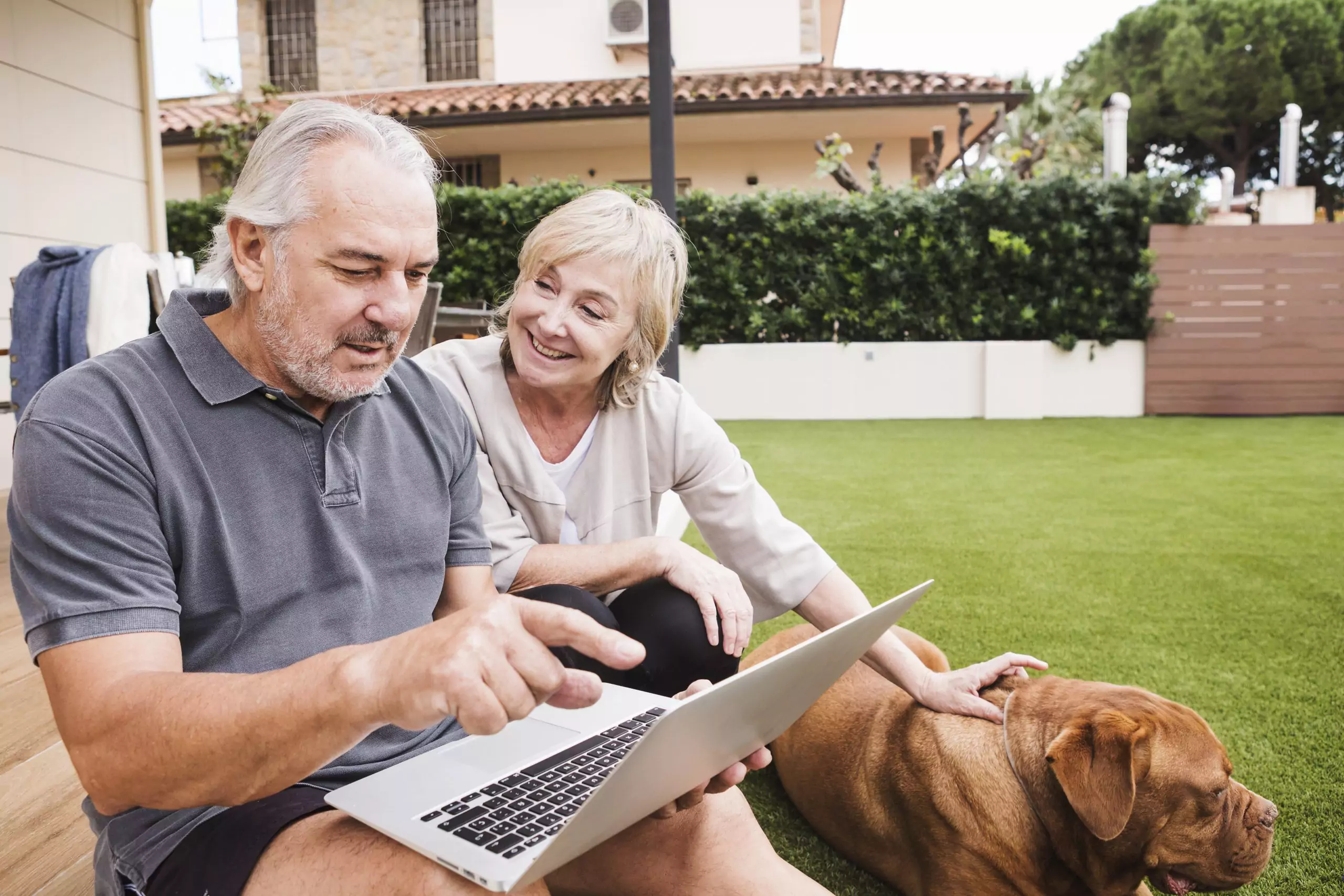 Older couple sits outside and reads information about stage 2 ckd on a laptop with their dog next to them