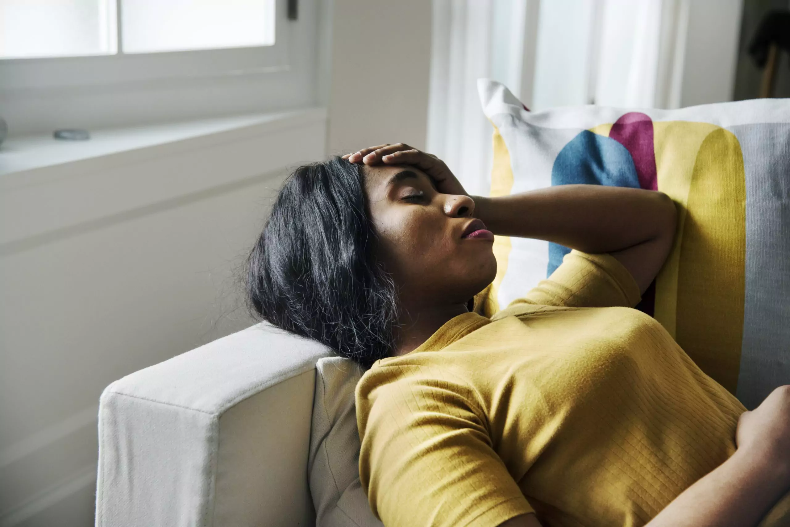 Black woman on sofa with hand on head worried about fibroids and asking for a second opinion