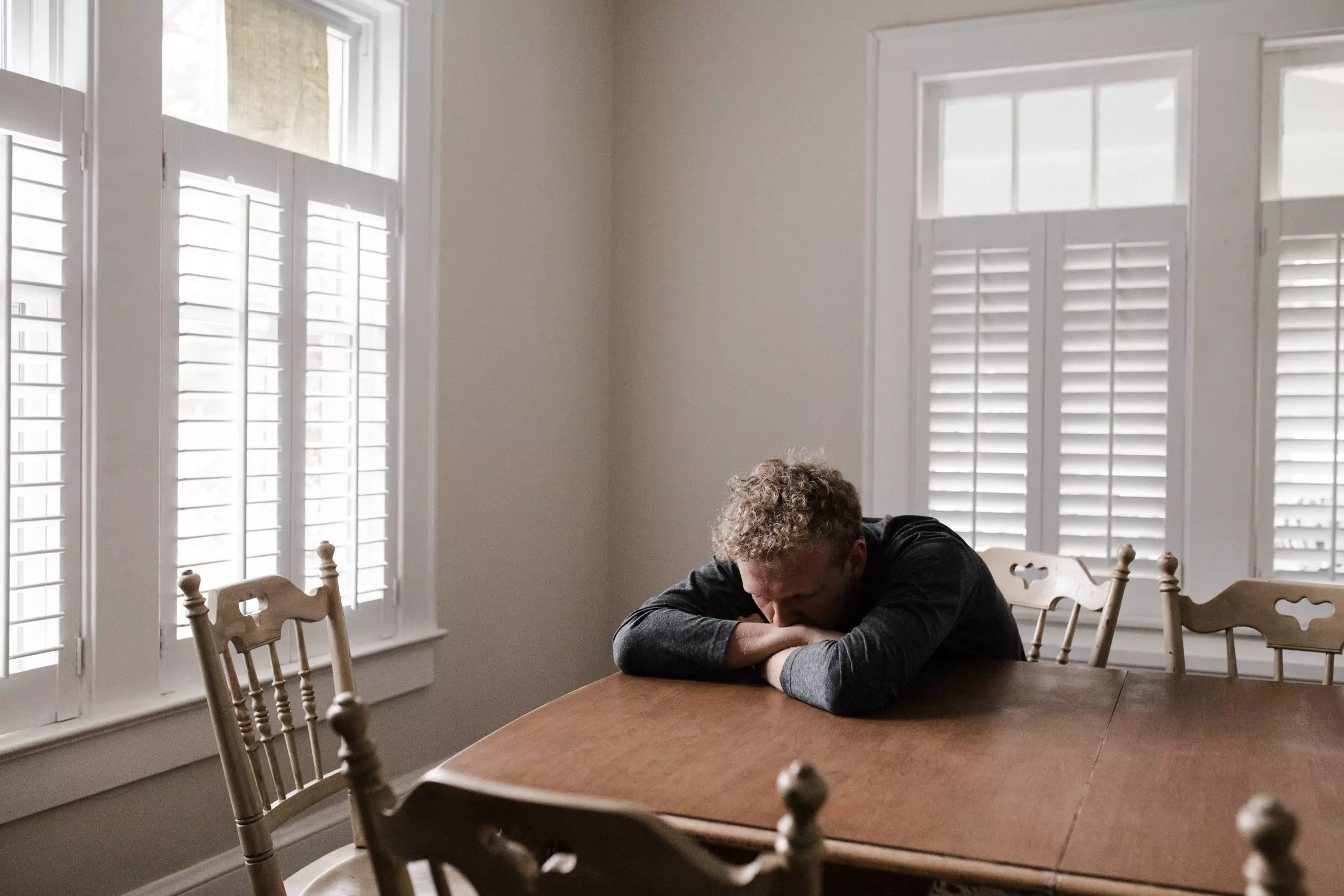 Man sitting down with head on table due to tiredness from stage 5 CKD