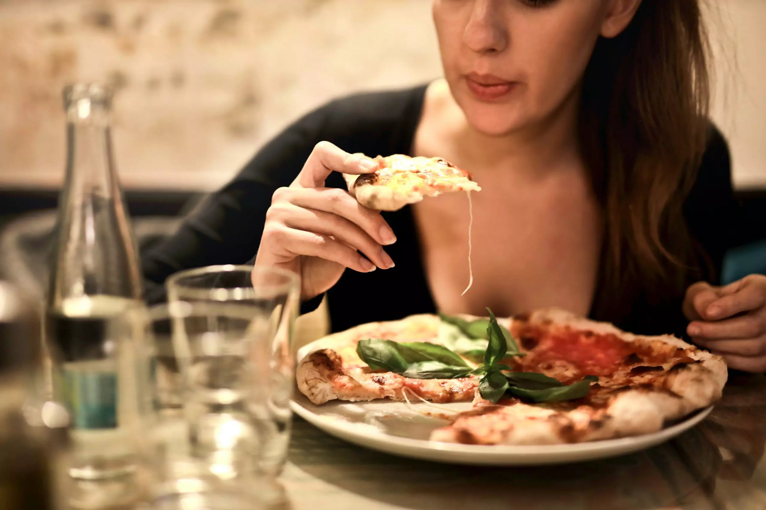 Woman eating pizza as a comfort food for fibroids symptoms