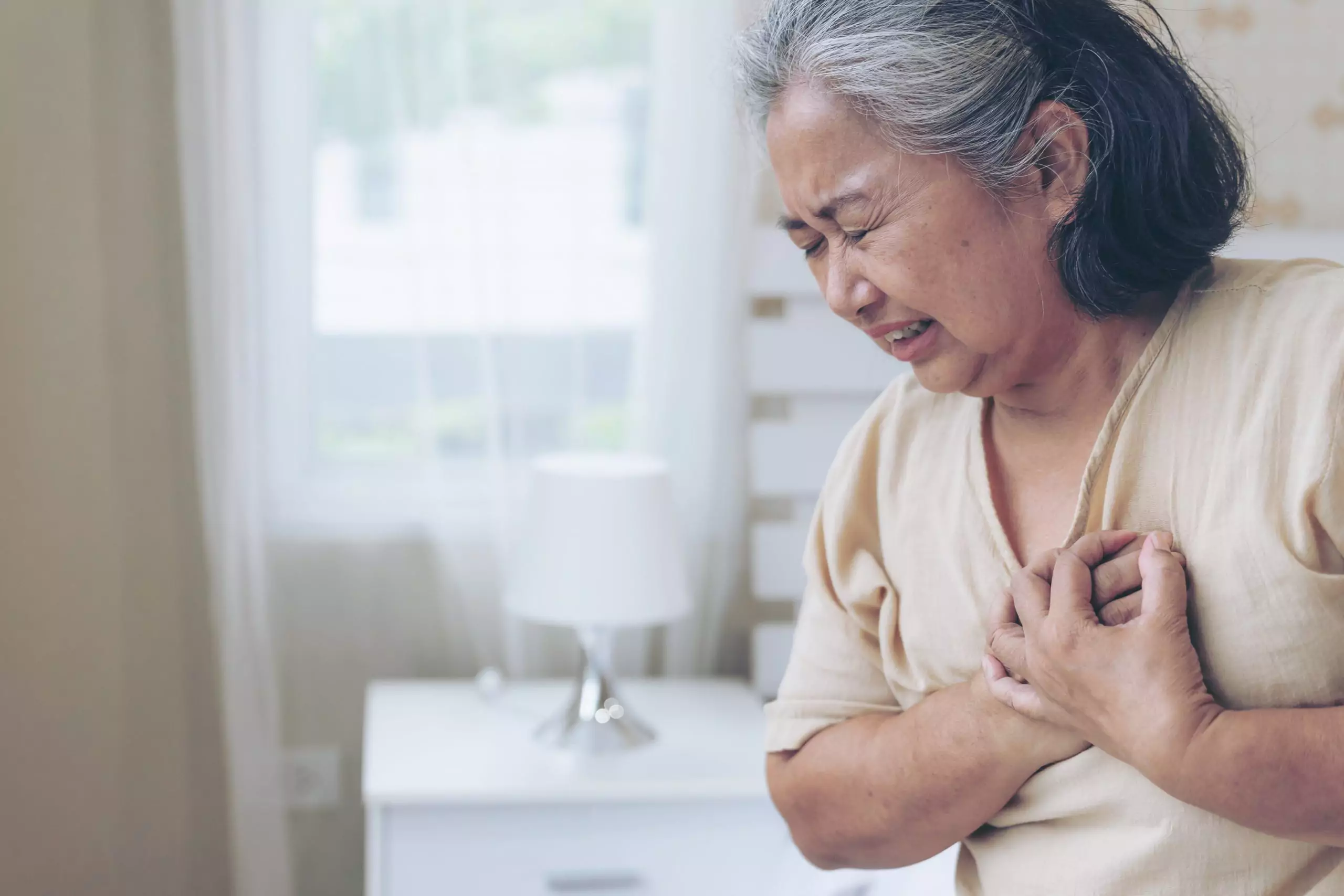 Asian woman clutching her chest from heart disease and CKD