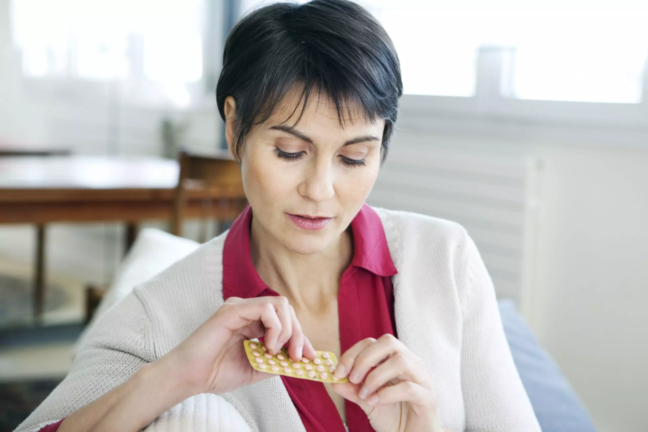 Senior woman looking at hormone replacement therapy pills for menopause symptoms treatment