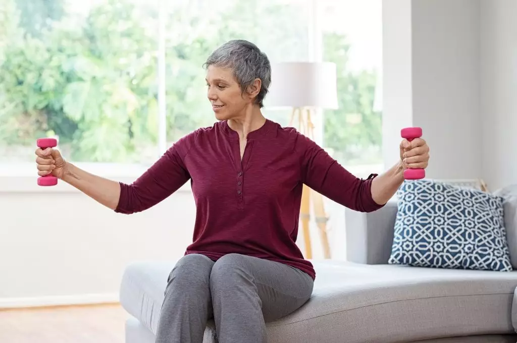 Senior Woman Lifting Weights And Working Out At Home Mature