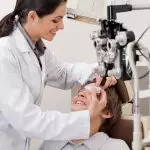 Smiling,Young,Optometrist,Putting,Eye,Drops,In,Eyes,Of,Patient