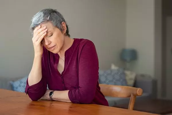 Senior,Woman,Suffering,From,Headache,While,Sitting,At,Table,In
